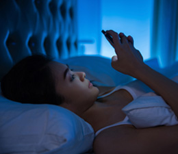 Woman playing phone in bed at night